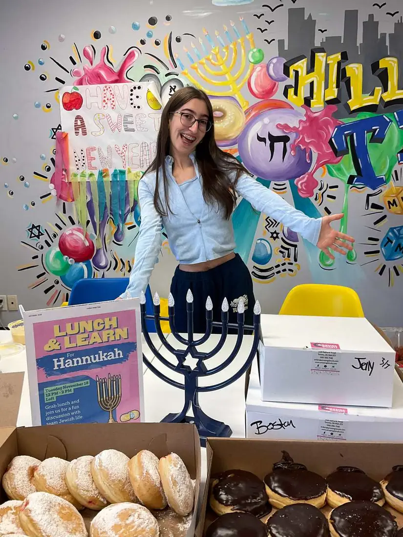 A student lighting the menorah at a Lunch & Learn Hannukah event