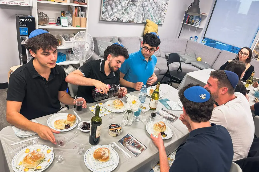 Students sharing a Shabbat meal across a long table