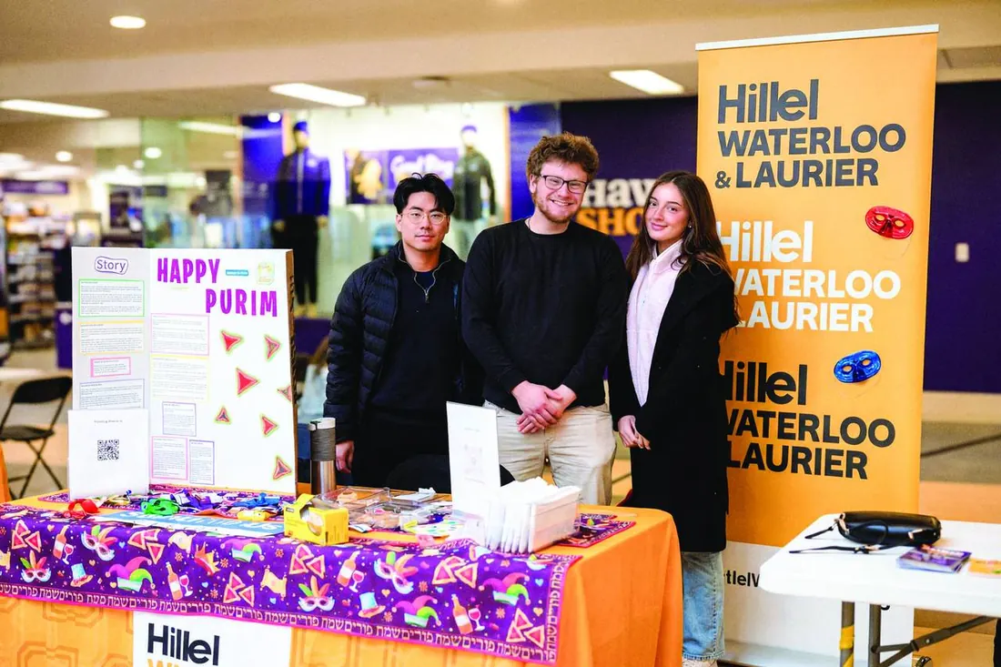Students tabling for Purim behind a Hillel Waterloo & Laurier banner