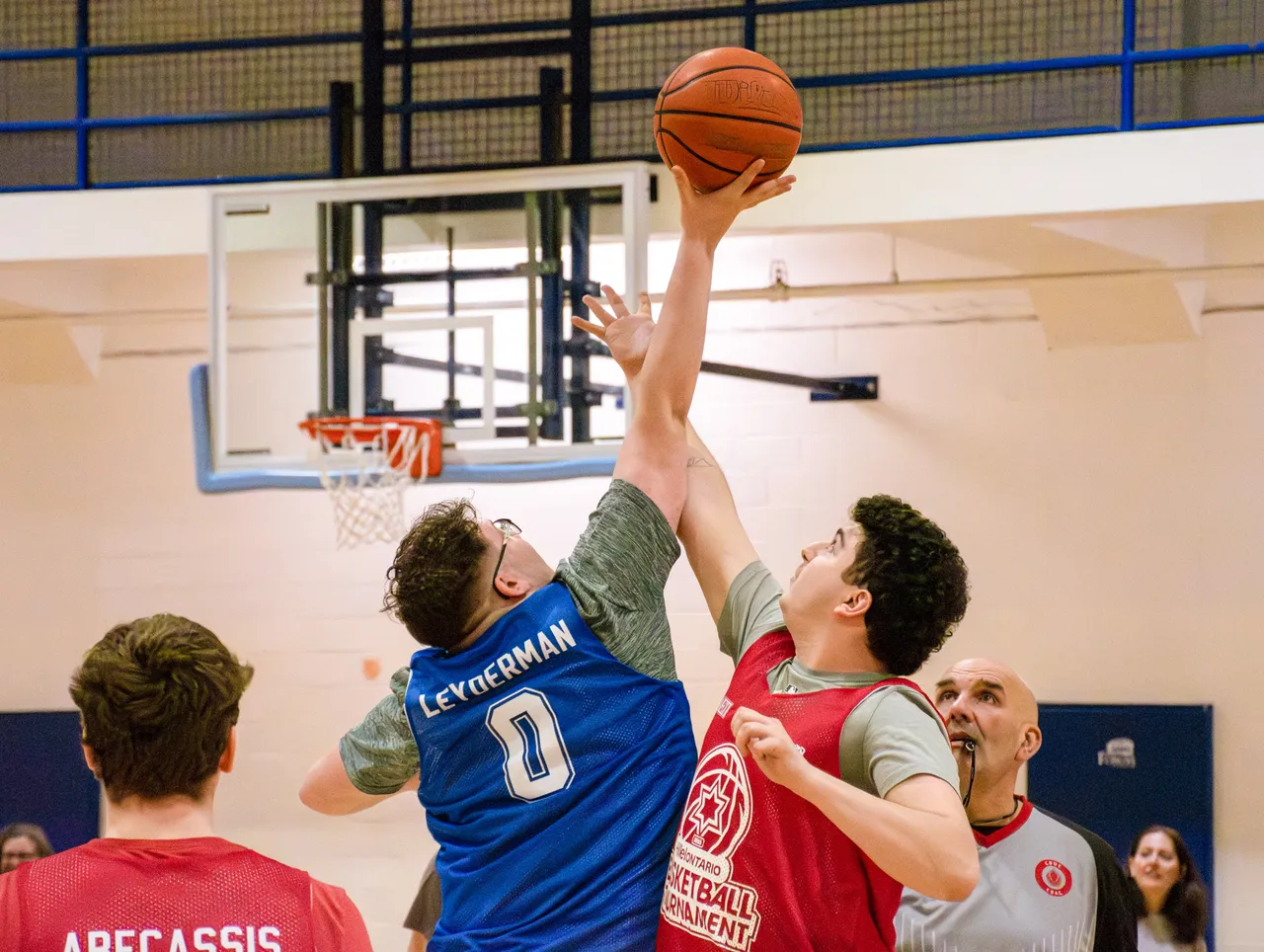 Players go up for the ball at the rim during a tournament game