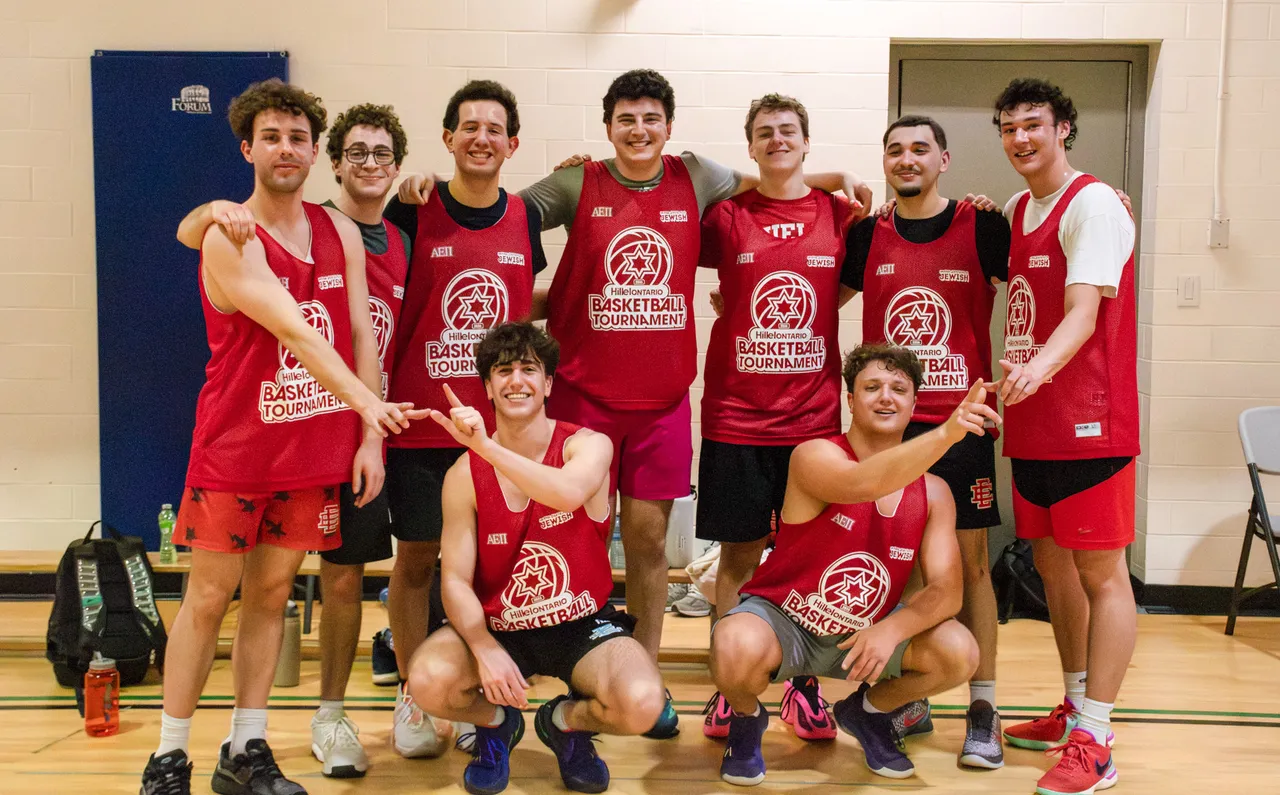 A team in red tournament jerseys poses together on the court