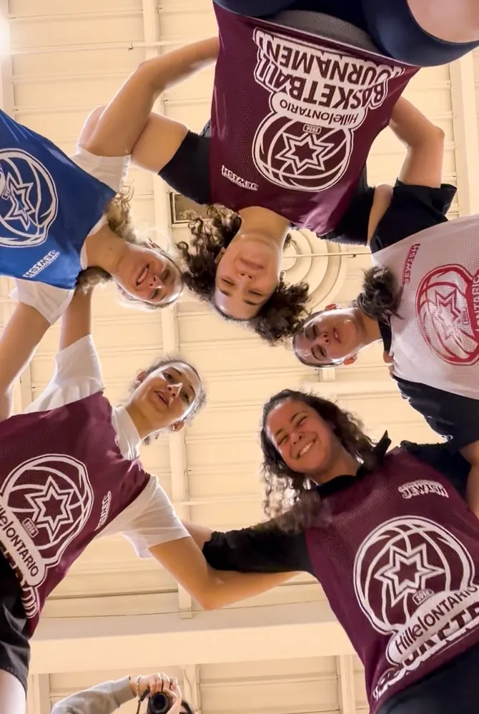 A team huddles up, arms around each other, at the Basketball Tournament