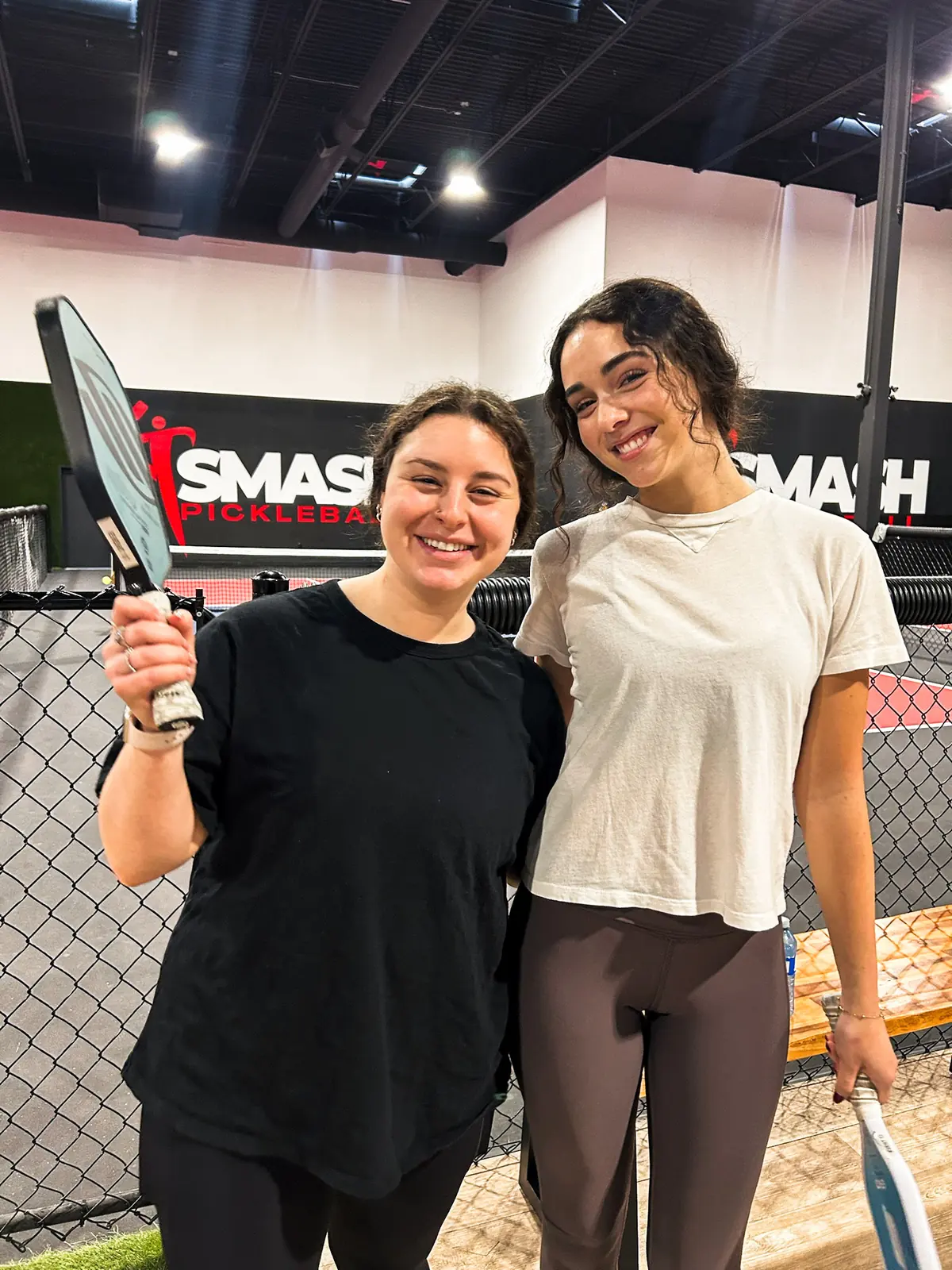 Two students smiling with their paddles at the SMASH pickleball tournament