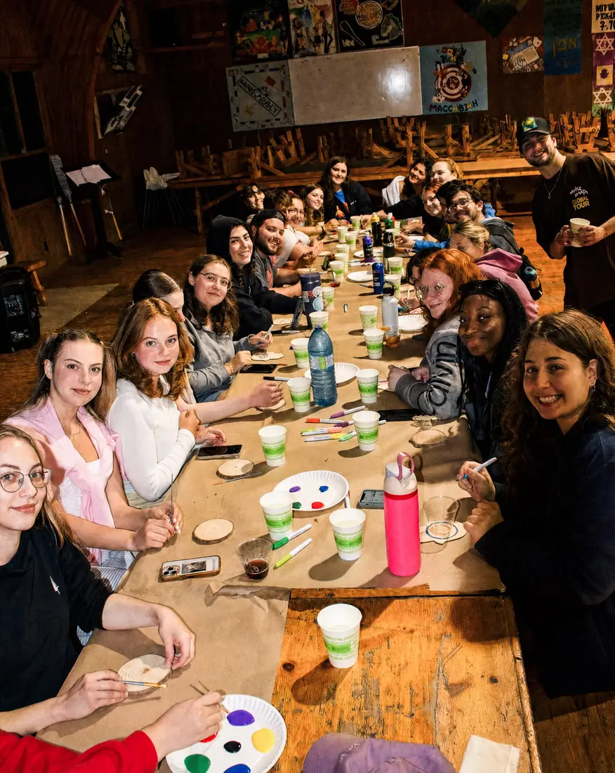 Campers painting together at a long table in the lodge