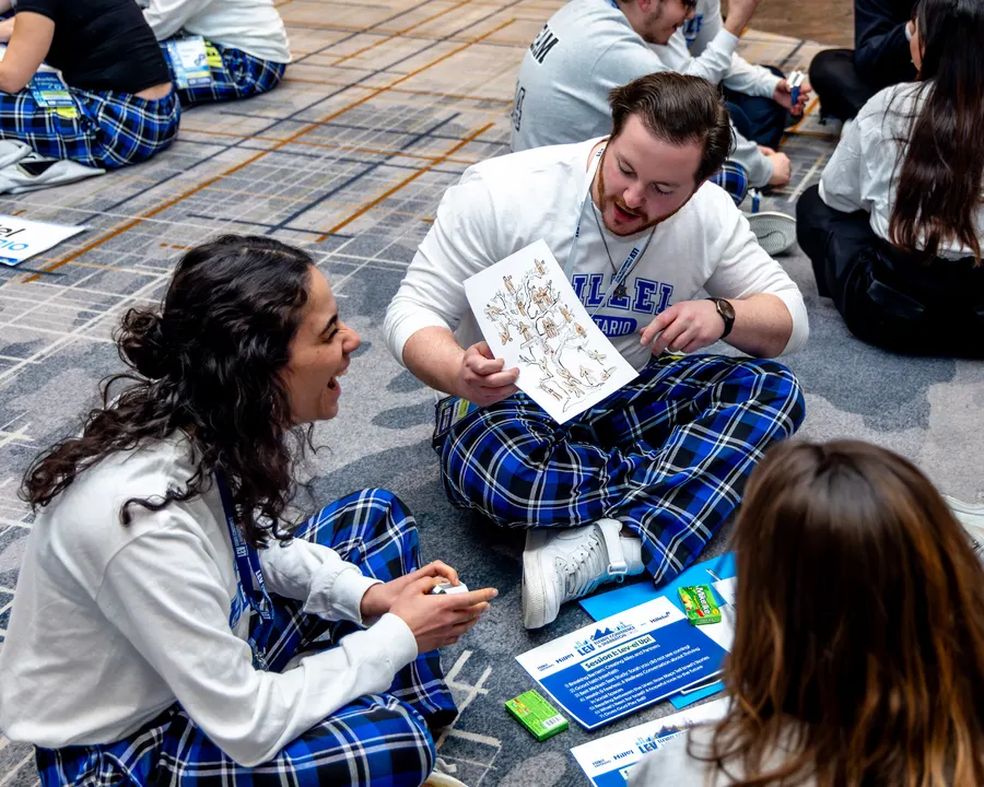 Two students in ELEVATE plaid compare notes on the ballroom floor