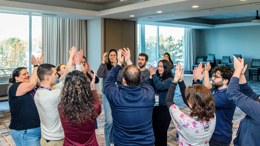 A circle of students with hands raised mid-song