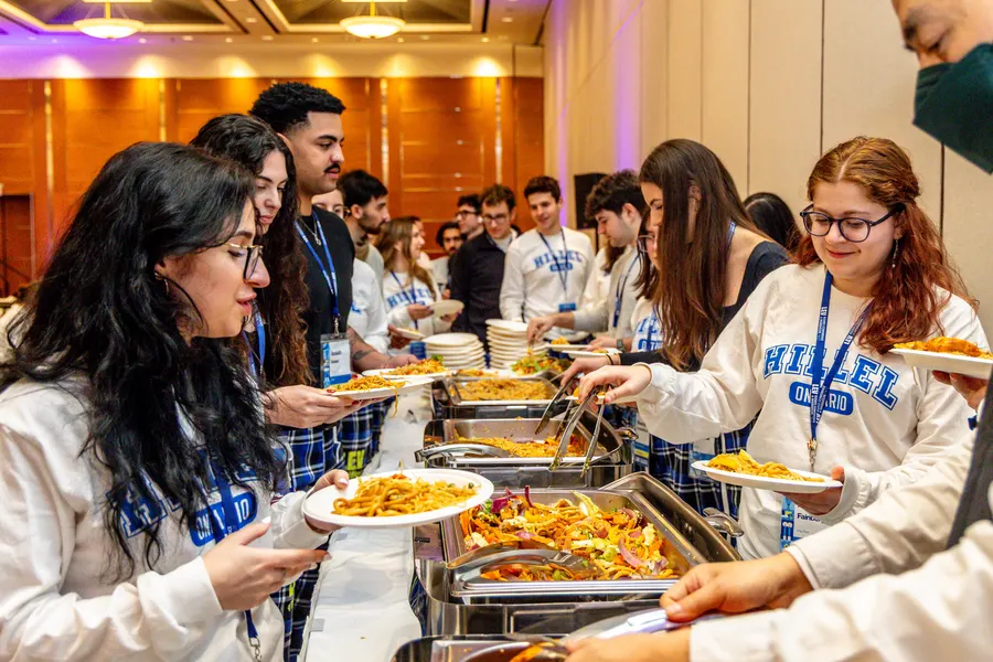 Students in matching sweaters line up at the Shabbat dinner buffet
