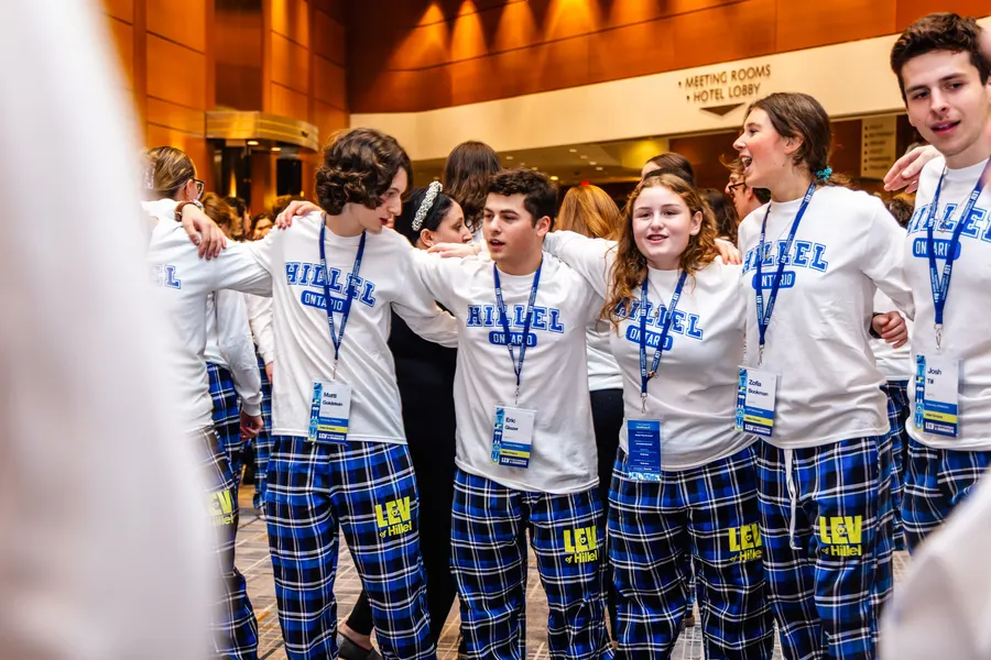 Students sing arm-in-arm in a circle