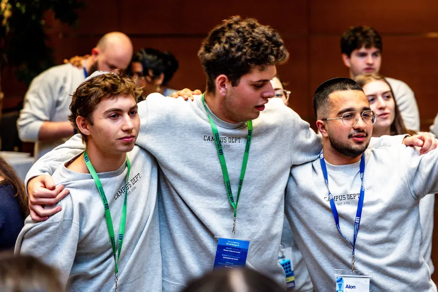 Three friends with lanyards, arms around each other