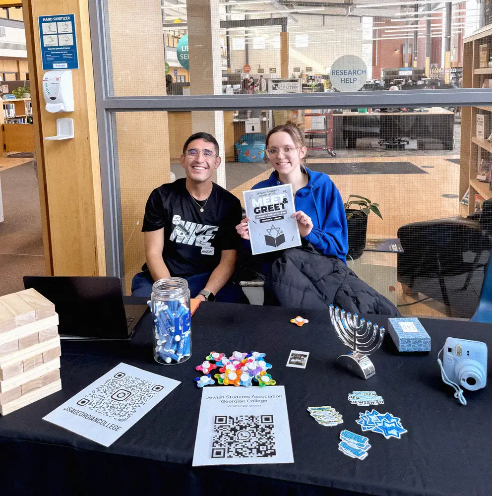 Students at a new Jewish club table with a menorah and giveaways