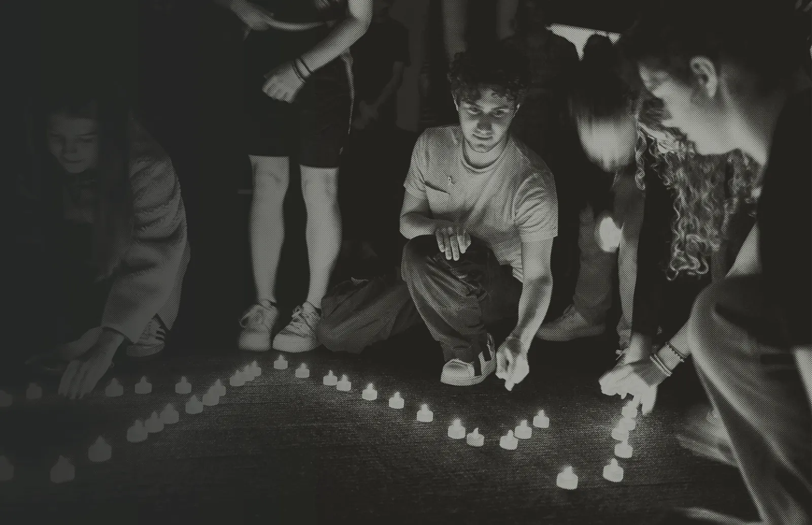 Students kneel to place memorial candles in the dark — the advocacy chapter cover