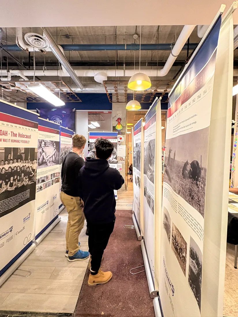 Students read the panels of a Holocaust education exhibit