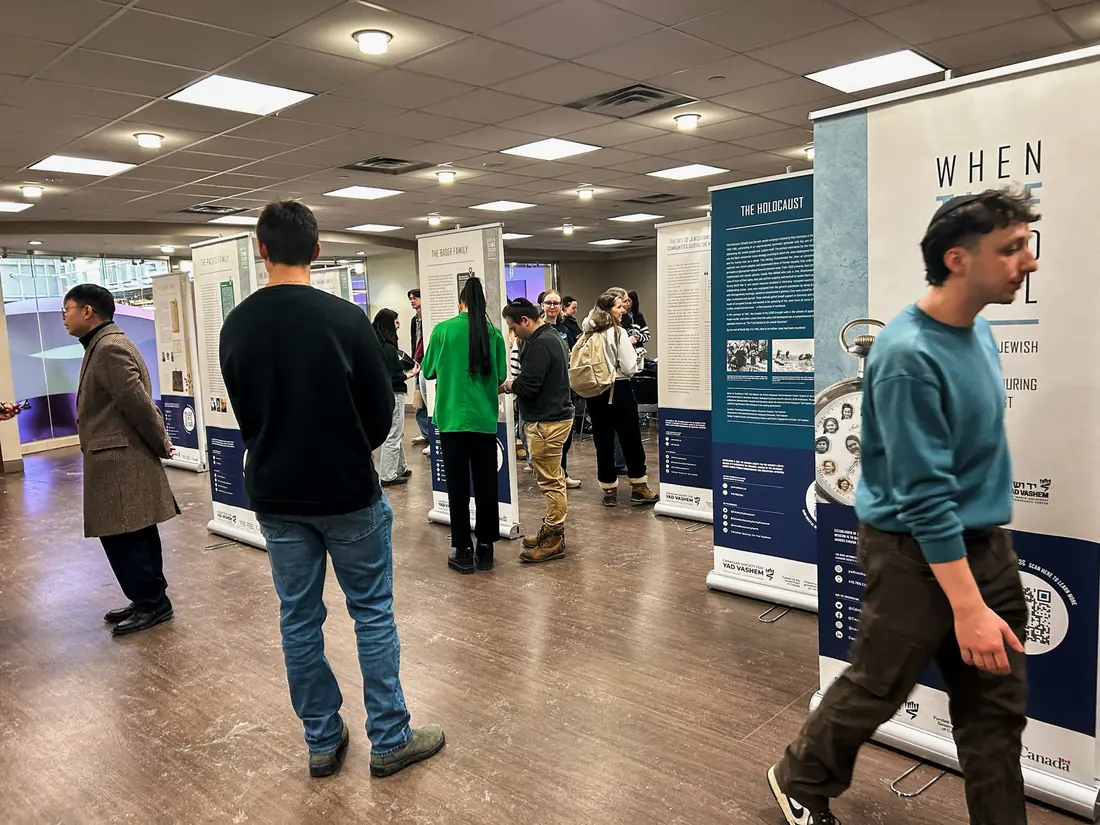 Students walk through a Holocaust education banner exhibit on campus