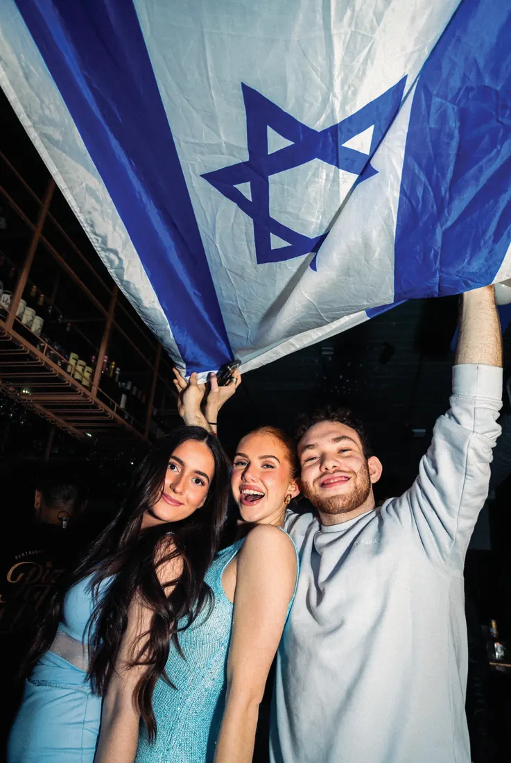 Two students hoist the Israeli flag overhead