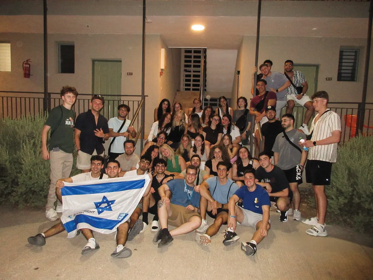 Students gathered at night with an Israeli flag