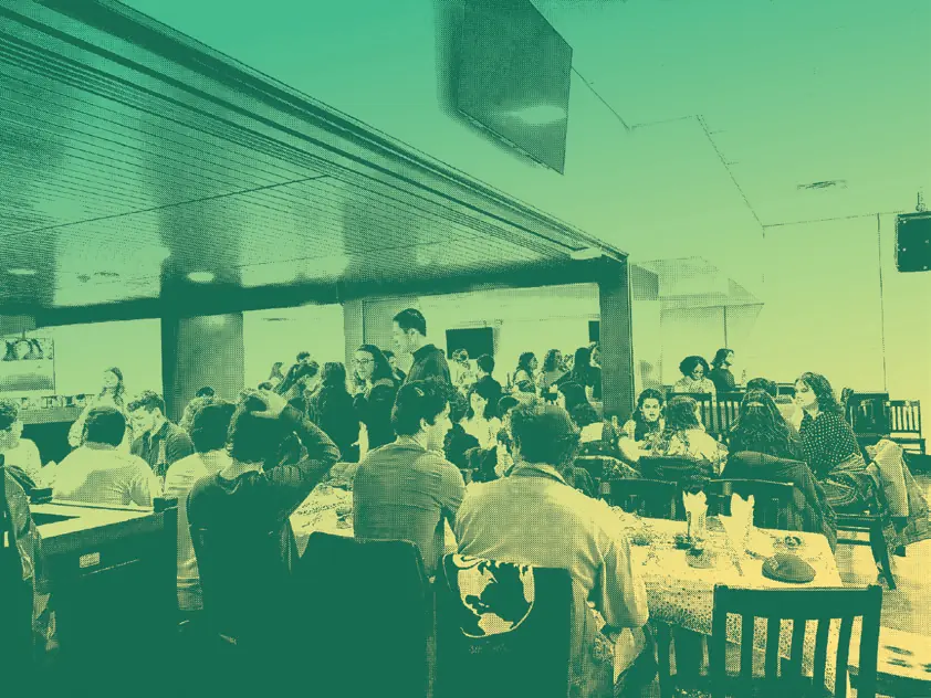 A crowded community Shabbat dinner at Hillel Waterloo, in green duotone